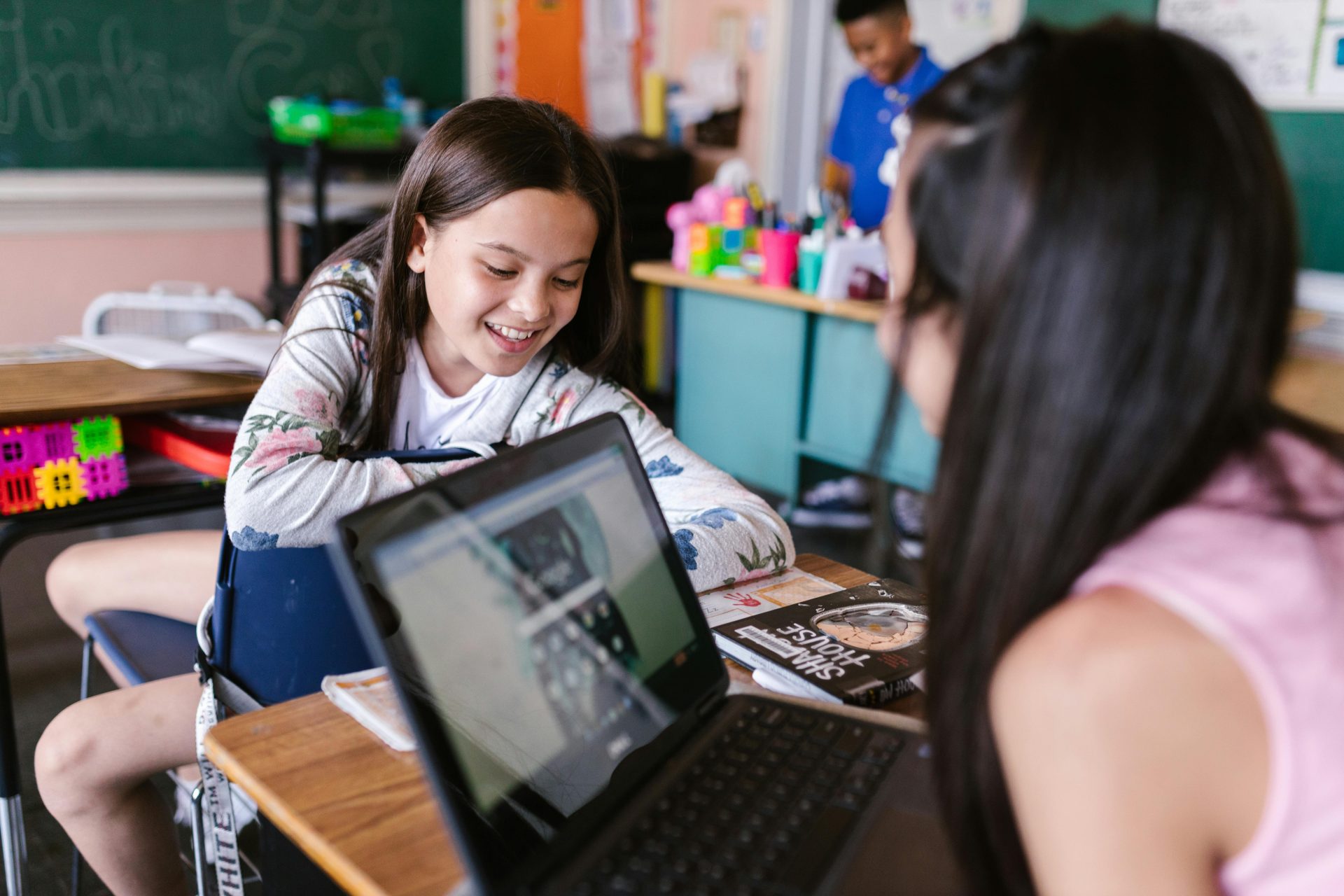 Children engaged in learning with a laptop in a vibrant classroom.